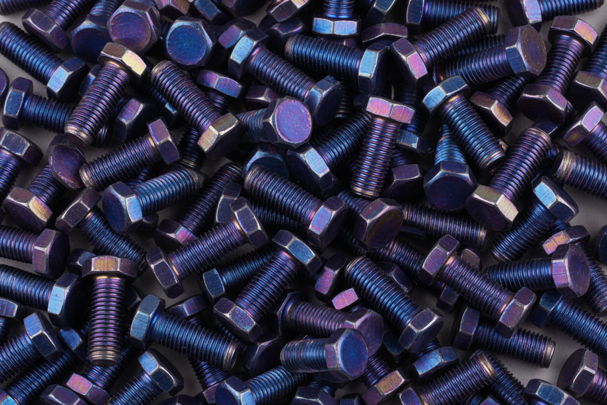 Créate a image full of burnt blue titanium bolts with a one sided hex head and the other side a flat side 